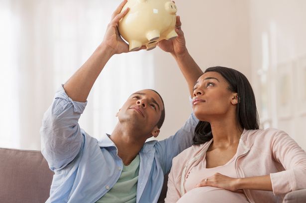 Young-parents-to-be-holding-piggy-bank-holding-piggy-bank-upside-down